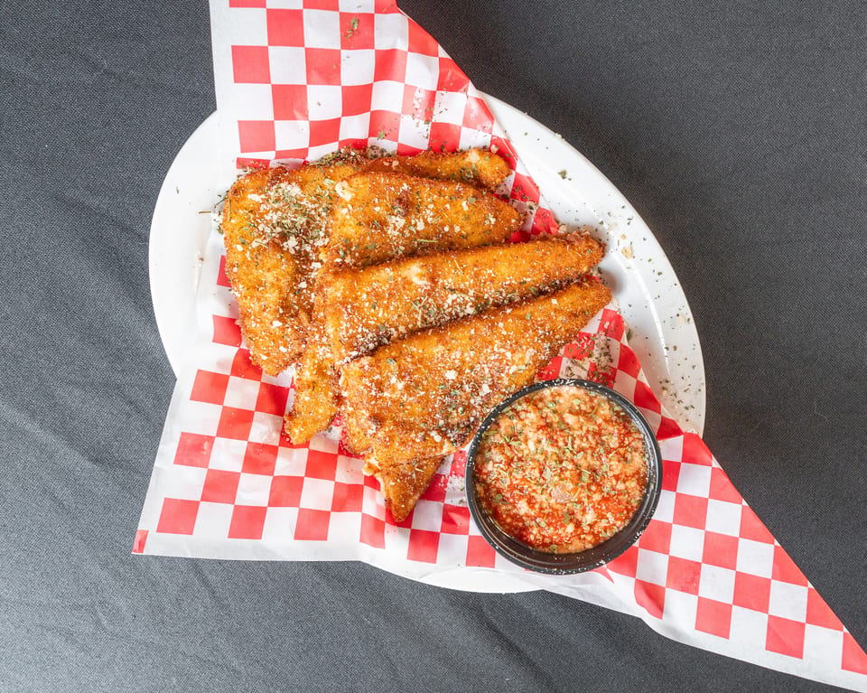 Golden-brown fried mozzarella sticks dusted with herbs and cheese, served with a side of marinara sauce.