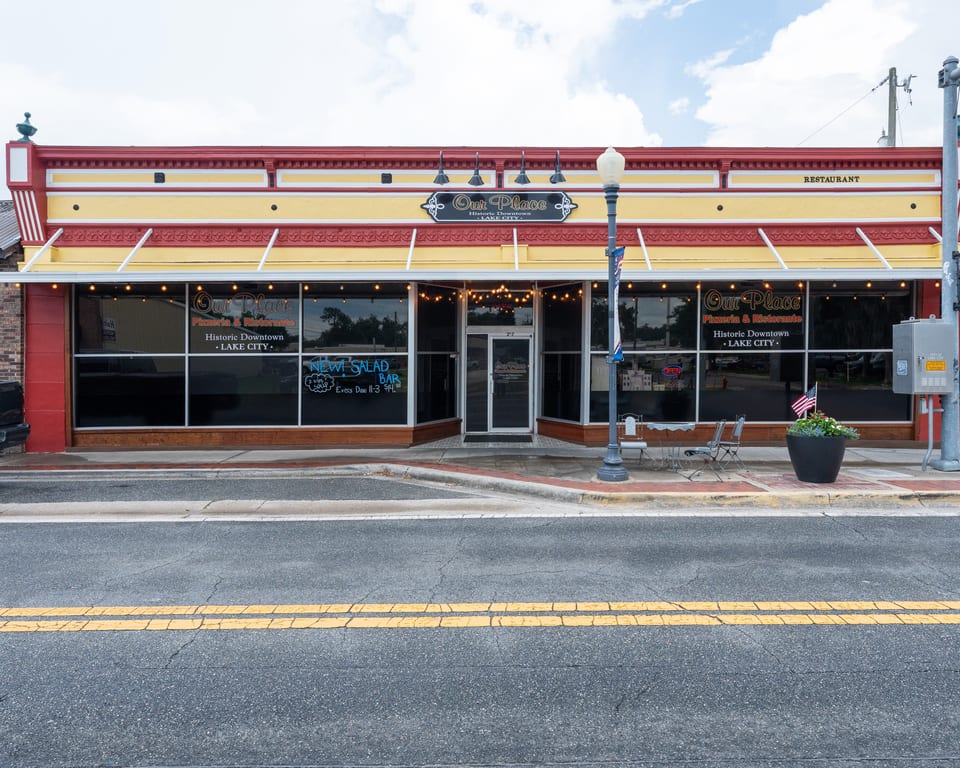 Our Place Pizzeria & Ristorante, a red and yellow building with large windows, on a sunny day.