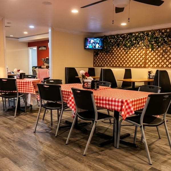Restaurant interior with red and white checkered tablecloths, black chairs, and booth seating.